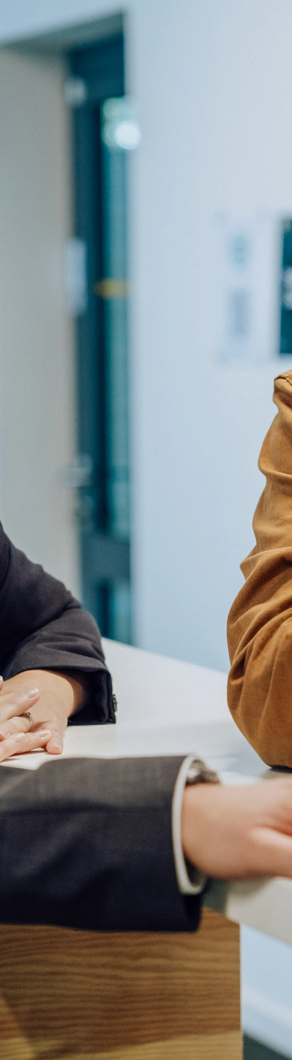 Three people in a business meeting discussing something on a laptop screen. One person is pointing at the screen while the others listen attentively.
